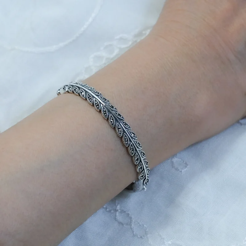 أسوارة ماركازيت فضة عيار 925 على المعصم تُظهر لمعان حجر البايرايت وتصميم الأوراق الكلاسيكي.