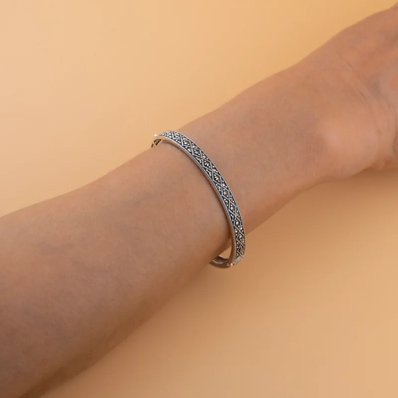 أسوارة ماركازيت فضة عيار 925 على المعصم بتصميم نقش دقيق وحبيبات بايرايت لامعة.