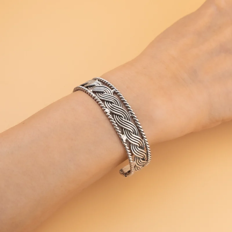 أسوارة فضة عيار 925 بنقشة ضفائر ملتوية على معصم اليد بتصميم مفتوح.