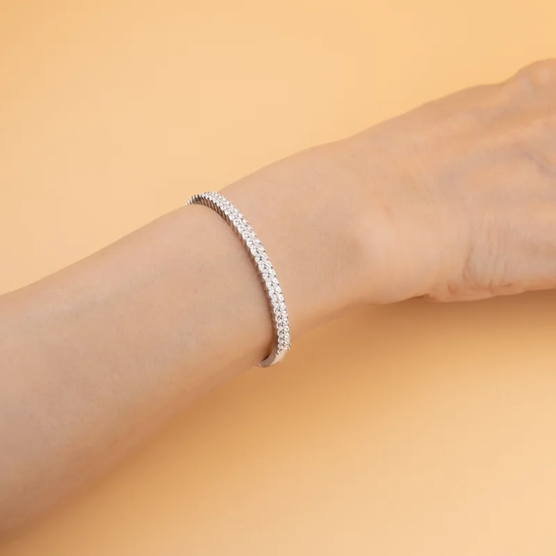 أسوارة فضة مرصّعة بزركون لامع على معصم اليد بتصميم قابل للفتح من الجانب.